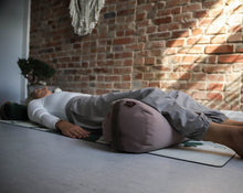 Załaduj obraz do przeglądarki galerii, Kobieta praktykująca jogę z zielonym wałkiem gryczanym pod głową i jasno różowym bolsterem pod kolanami