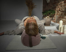 Załaduj obraz do przeglądarki galerii, Kobieta leżąca na jasno różowym wałku gryczanym ułożonym wzdłuż kręgosłupa