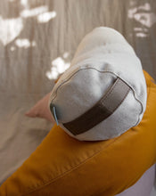 Load image into Gallery viewer, mały wałek gryczany w pokrowcu z lnu i bawełny w kolorze piaskowym leżący na żółtej poduszce księżycowej