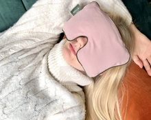 Load image into Gallery viewer, kobieta wypoczywająca na sofie leżąc na pomarańczowej poduszce gryczanej z różową poduszką relaksacyjną na oczach