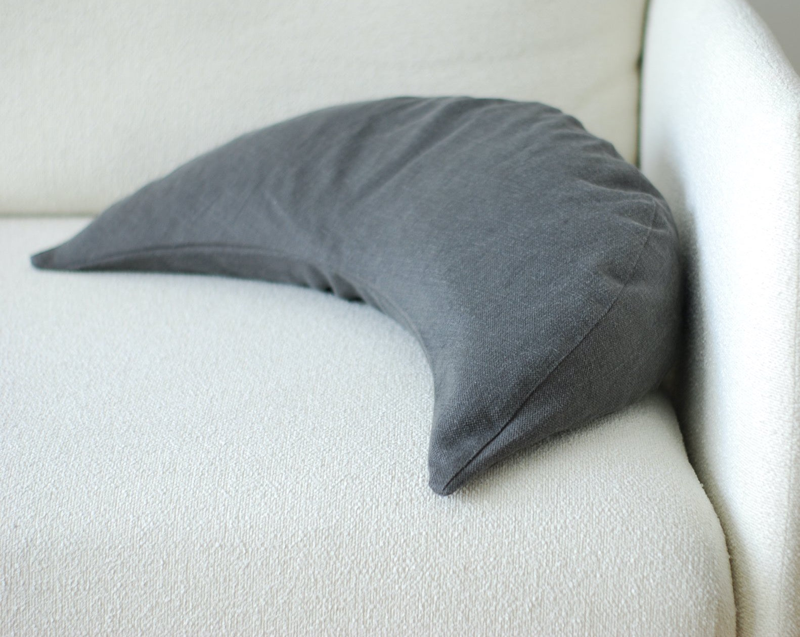 poduszka księżycowa z naturalnej tkaniny z lnu i bawełny w kolorze grafitowym leżąca na jasnej kanapie