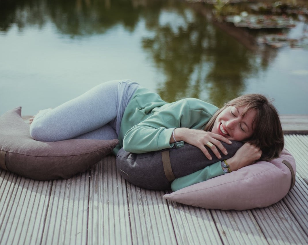 kobieta leżąca na pomoście z trzema poduszkami księżycowymi wypełnionymi gryką