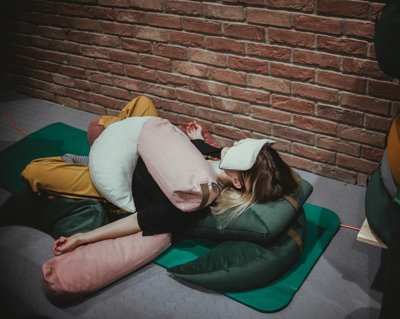 kobieta praktykująca relaksację leżąc na macie używając poduszek gryczanych jako odciążenie o obciążenie ciała