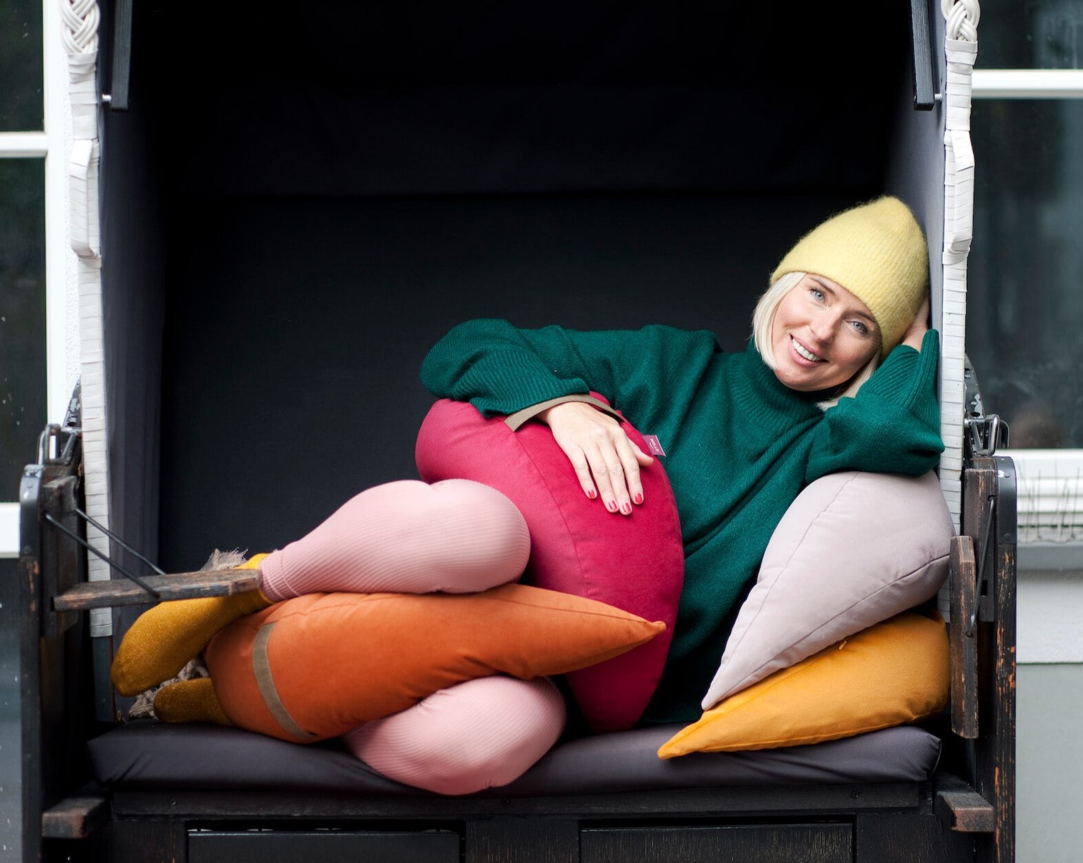 szczęśliwa kobieta leżąca wśród kolorowych poduszek wypełnionych gryką