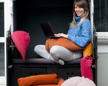 Załaduj obraz do przeglądarki galerii, kobieta siedząca przed komputerem otoczona poduszkami  w kolorze pomarańczowym, różowym i żółtym wypełnione gryką

