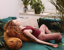 Load image into Gallery viewer, kobieta medytująca na łóżku opierając plecy na żółtym wałku gryczanym i poduszce kopertowej wypełnionej pianką poliuretanową
